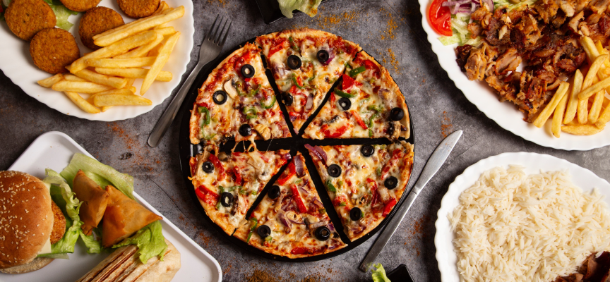 Top-down view of popular cuisines including cheesy pizza, fast food burgers, fries, rice, and Arabic kebabs available for food delivery.